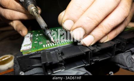 Nahaufnahme eines Technikers, der einen Lötkolben zur Reparatur einer Leiterplatte verwendet, um technisches Know-how und Präzision zu demonstrieren Stockfoto