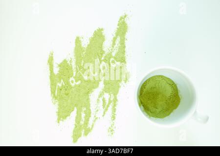 Teetasse mit weißer Oberfläche, auf der sich auffällige gelbe Flecken von grünem Matcha-Tee befinden. Hellgrünes Pulver. Gemahlenes Pulver von grünem Tee Spezia Stockfoto