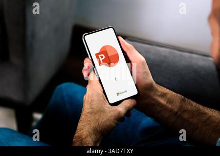 Mann, der ein Mobiltelefon verwendet, das das Logo von Microsoft Office PowerPoint auf dem Bildschirm anzeigt. PowerPoint ist ein Präsentationsprogramm. ROSARIO, ARGENTINIEN - APR Stockfoto