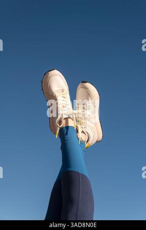 Sportschuhe vor blauem Himmel, Beine hoch Stockfoto