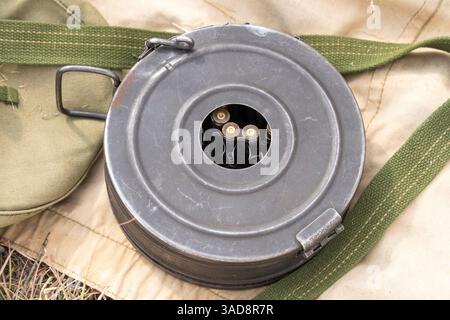 Sowjetische PPS-Maschinenpistole aus dem Zweiten Weltkrieg mit sichtbarem Schlagzeug-Magazin und Kugeln auf militärischer Leinwand Stockfoto