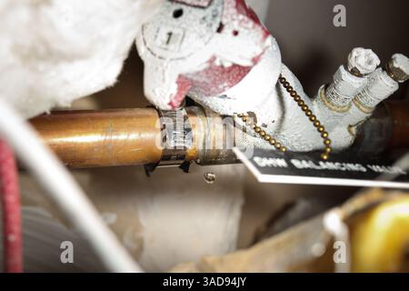 Provisorische Befestigung der Wasserleitung in der Decke mit Stahlschelle. Wasserleckage tropft immer noch. Installationskonzept oder Heimwerker. Auch bekannt als Wurmantrieb Stockfoto