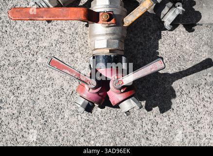 Durchflussventile für gewerbliche Wasserpumpen und an den Griffen. Draufsicht. Kommerzielle Pumpvorrichtung auf dem Gehweg, um Wasser von einem Ort zum anderen zu bewegen. Auswahl Stockfoto
