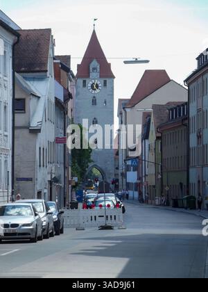 Blick auf die Straße mit einem historischen Uhrenturm am Ende der Straße. Die Szene umfasst geparkte Autos, Gebäude mit traditioneller Architektur und ein Stockfoto
