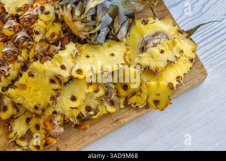 Nahaufnahme einer frisch geschälten und geschnittenen Ananas auf einem hölzernen Schneidebrett. Lebendiges und detailreiches Foto von tropischer Frische, perfekt für culina Stockfoto