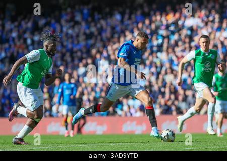 Glasgow, Großbritannien. April 2025. Rangers FC spielte Hibernian FC im Ibrox Stadium, Glasgow, dem Heimstadion der Rangers, in einem Spiel der William Hill Premiership. Das Endresultat waren die Rangers FC 0:2 Hibernian FC. Imager von Cyriel Dessers (R9), der mit dem Ball läuft und von Rocky Bushiri (H33) verfolgt wird Credit: Findlay/Alamy Live News Stockfoto