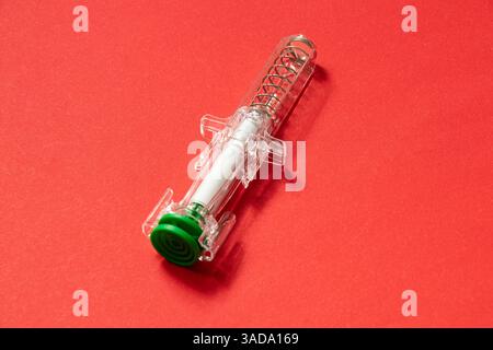 Die Fertigspritze liegt auf rotem Hintergrund, Spritze für Injektionszwecke, Arzneimittel und Behandlung Stockfoto