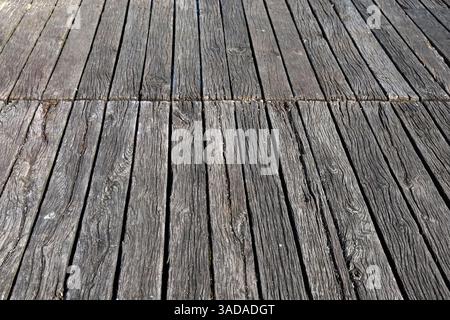 Parallel verwitterte Holzdielen bilden eine strukturierte Oberfläche, die Alterserscheinungen und Witterungseinflüsse aufweist Stockfoto