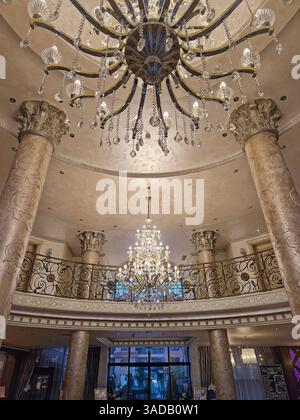 Opulente Innenausstattung mit großen verzierten Säulen und großen Kronleuchtern, die von der detailreichen Decke hängen. Luxuriöse Lobby-Umgebung strahlt Eleganz aus Stockfoto