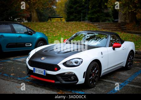 Turin, Italien - 08. November 2021: Ein weißes Abarth 124 Spider Cabriolet mit schwarzer Kapuze und roten Akzenten parkt auf einem Parkplatz Stockfoto