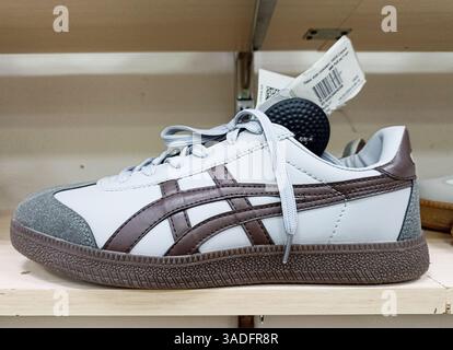 Aktau, Kasachstan - 22. März 2025: Grau-brauner Sneaker auf dem Regal mit Etikett. Stockfoto