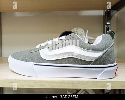 Aktau, Kasachstan - 22. März 2025: Skateboardschuh aus grauem Wildleder mit weißem Streifen auf dem Regal. Stockfoto