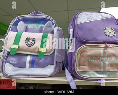 Aktau, Kasachstan - 22. März 2025: Niedliche lila Kinderrucksäcke mit Zeichentrickmotiven im Regal. Stockfoto