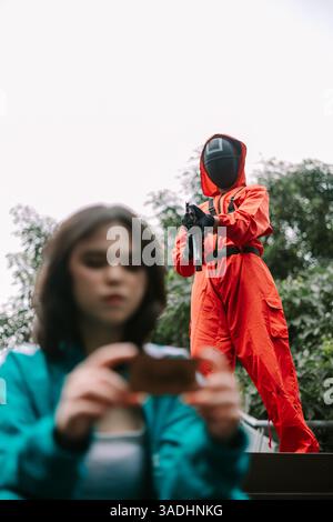 Jakarta, Indonesien, 4. April 2025. Eine verschwommene Frau nimmt mit ihrem Handy ein Foto von einer Person in rotem Anzug und Maske auf, die mit einem posiert Stockfoto