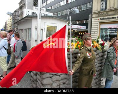 3. September 2005; Berlin, DEUTSCHLAND; Ein Modell in sowjetischer Uniform hält am Berliner Checkpoint Charlie eine sowjetische Flagge. Der Kontrollpunkt befand sich im alten US-Sektor in West-Berlin und war der letzte der drei Kontrollpunkte in West-Berlin, die man nutzen konnte, um nach Ost-Berlin zu gelangen. . (Kreditbild: Bill Putnam/ZUMAPRESS.com) Stockfoto