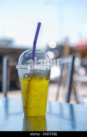 Eistee mit Chrysanthemen in einem Plastikbecher mit Strohhalm auf dem Tisch Stockfoto