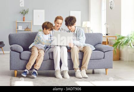 Mom mit zwei Söhnen, die auf dem Sofa sitzen, mit einem Laptop, Nahaufnahme Stockfoto