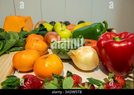 Ein Tisch voller Obst und Gemüse, einschließlich Äpfel, Orangen, Erdbeeren und Paprika. Stockfoto