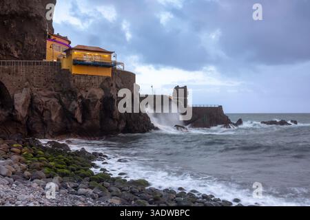 Gebäude über dem steinigen Strand in Ponta do Sol, Insel Madeira, Portugal, am Abend Stockfoto