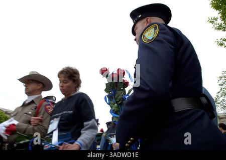 Mai 2005; Washington, DC, Vereinigte Staaten; ein Polizeibeamter des Bundesstaates New Jersey steht in einem spontanen Ehrenband, während die Überlebenden von Polizeibeamten, die 2004 im Dienst getötet wurden, während der 17. jährlichen Nationalen Polizeiwoche bei Kerzenlicht im National Law Enforcement Officers Memorial 13. Mai 2005 in Washington, DC zu einer Gedenkfeier begleitet werden. US-Staatsanwalt Alberto Gonzalez verlas die Keynote-Ansprache an eine Menge von Polizeibeamten, (nach Schätzungen über 20.000), und Überlebende dieser Offiziere, Männer und Frauen, die das ultimative Opfer gebracht haben. . Stockfoto