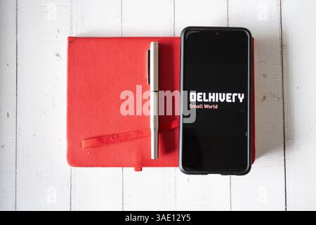 Mobiltelefon mit App-Bildschirm für E-Commerce-Logistik-Startup Delhivery, das auf rotem Tagebuch sitzt und Geschäftsabschlüsse zeigt Stockfoto