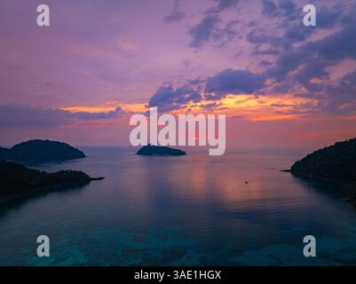 Ein atemberaubender Blick aus der Luft auf die tropischen Inseln, umgeben von ruhigem Meereswasser bei Sonnenuntergang. Die goldenen Töne des Himmels spiegeln sich auf dem Wasser und erzeugen einen Stockfoto