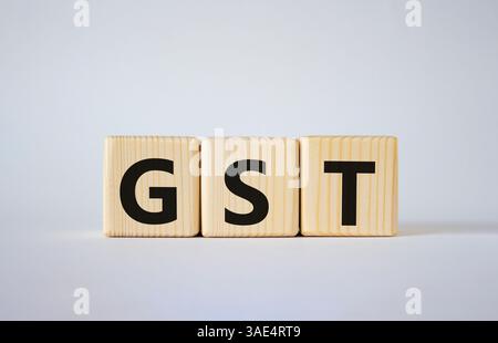 GST – Steuersymbol für Waren und Dienstleistungen. Konzeptwort GST auf Holzwürfeln. Schöner weißer Hintergrund. Business- und GST-Konzept. Kopierbereich. Stockfoto