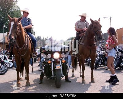 August 2000; Hulett, Wyoming, USA; Jackson, Wyos berittene Offiziere ALAN JOHN (L) und RON MILLER mussten sich bei der jährlichen „Ham and Jam“-Feier mit Bikern und Babes auseinandersetzen. Ihre gut ausgebildeten Pferde Zeus und Badger haben die Massen im Schritt bewältigt. (Bild: Alan Carroll/ZUMAPRESS.com) Stockfoto