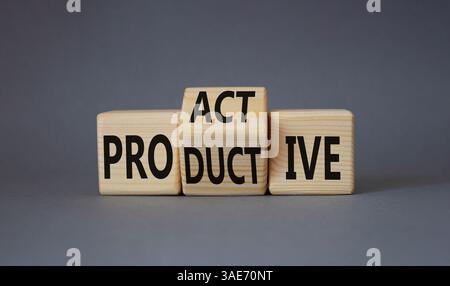 Proaktives und produktives Symbol. Gedrehte Holzwürfel mit Worten produktiv und proaktiv. Schöner grauer Hintergrund. Geschäftskonzept. Kopierbereich Stockfoto