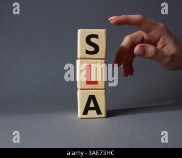 SLA - Service Level Agreement. Holzwürfel mit Wort SLA. Geschäftsmann Hand. Schöner grauer Hintergrund. Business- und Service Level Agreement-Konzept. Stockfoto