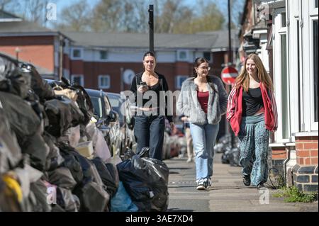 Dale Road, Selly Oak, Birmingham, 6. April 2025: Studenten gehen an einer Mauer voller Müllsäcke entlang der Dale Road, Selly Oak, vorbei. - Überfüllte Müllsäcke auf dem Bürgersteig im Studentenbereich bei Selly Oak nahe der Universität Birmingham. Die Sammlungen fanden seit Wochen nicht statt, und einige Bereiche haben Müllwände von 5 Fuß Höhe. Quelle: British News und Media/Alamy Live News Stockfoto