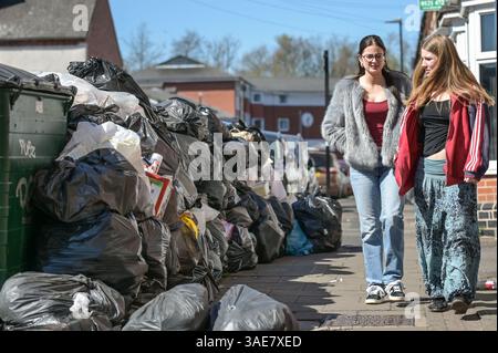 Dale Road, Selly Oak, Birmingham, 6. April 2025: Studenten gehen an einer Mauer voller Müllsäcke entlang der Dale Road, Selly Oak, vorbei. - Überfüllte Müllsäcke auf dem Bürgersteig im Studentenbereich bei Selly Oak nahe der Universität Birmingham. Die Sammlungen fanden seit Wochen nicht statt, und einige Bereiche haben Müllwände von 5 Fuß Höhe. Quelle: British News und Media/Alamy Live News Stockfoto