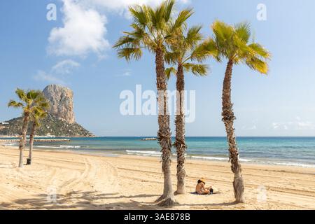 Calpe. Spaniens Costa Blanca Küste. Ein Stadtstrand mit Palmen und einem Gipfel namens Penon de Ifach (kleiner Giblartar) Stockfoto