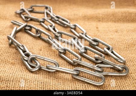 Ein Stück Metallkette auf Jute-Tuch, Makro. Stockfoto