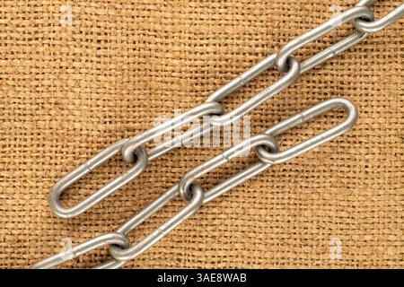Ein Stück Metallkette auf Jute-Tuch, Makro, Draufsicht. Stockfoto