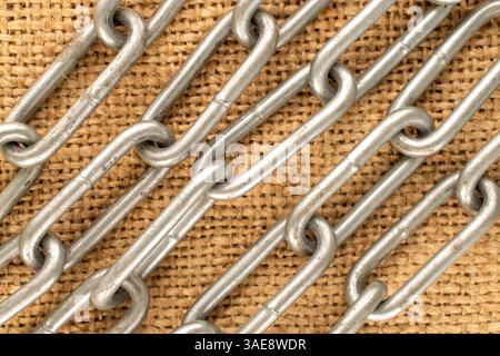 Ein Stück Metallkette auf Jute-Tuch, Makro, Draufsicht. Stockfoto