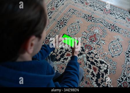 Ein Kerl mit einem Smartphone in der Hand und dem grünen Bildschirm Stockfoto