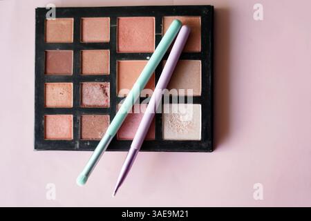 Make-up-Palette mit Pinseln auf hellrosa Hintergrund Stockfoto