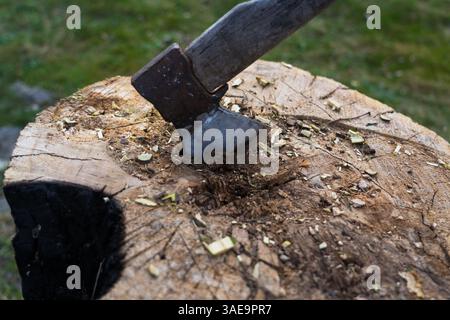 Die Axt ist in einen Eichenblock gehämmert. Axt steckt im Deck fest Stockfoto