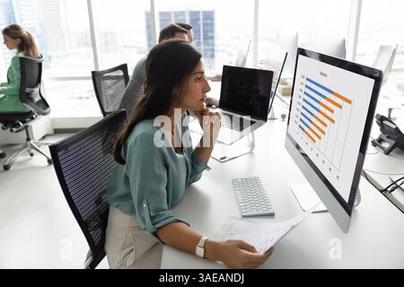 Ernsthafte junge Lateinanalytikerin, die an statistischen Forschungsergebnissen arbeitet Stockfoto