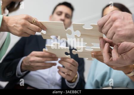 Junges Business-Team, das Teile von Stichsägen von unten zusammenfügt Stockfoto