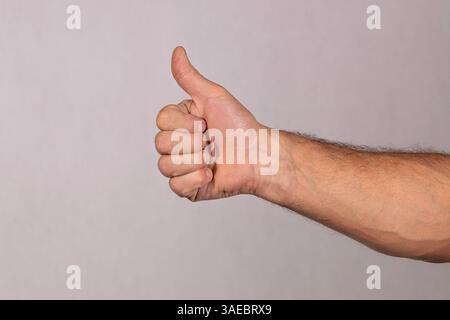 Haarige kaukasische männliche Hand mit Daumen nach oben in einer OK-Schild-Handfläche nach vorne Stockfoto