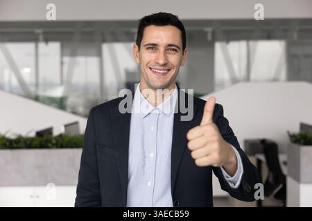 Glücklicher lateinamerikanischer Geschäftsführer, der vor der Kamera den Daumen hoch zeigt Stockfoto
