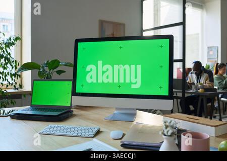 Desktop-Computer und Laptop mit Chromakey-Bildschirmen stehen am Arbeitsplatz eines modernen Programmierers oder Designers Stockfoto