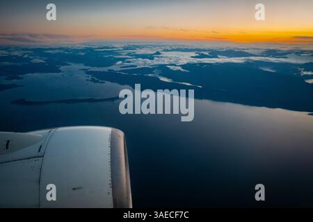 Flugzeugflügel und -Motor fliegen bei Sonnenaufgang über der Straße von Georgia in British Columbia, Kanada. Stockfoto