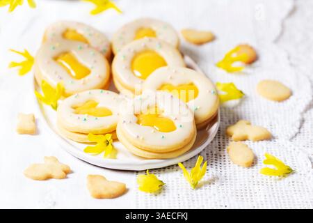 Ostereierkekse mit Zitronenorangenquark, bedeckt mit weißer Glasur und Forsythienblüten. Stockfoto