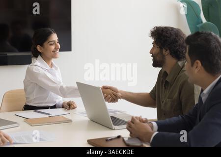 Indische Frau schüttelt Hand, Kollege, grüßt einander im Vorstandssitz Stockfoto