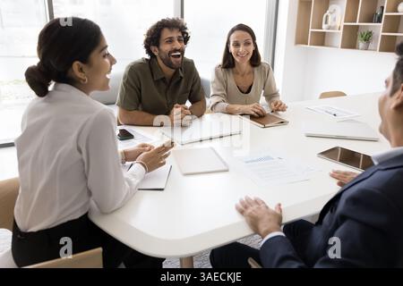 Vier Arbeitskollegen nehmen an der Gruppenbesprechung Teil, lachen und scherzen sich im Sitzungssaal Stockfoto