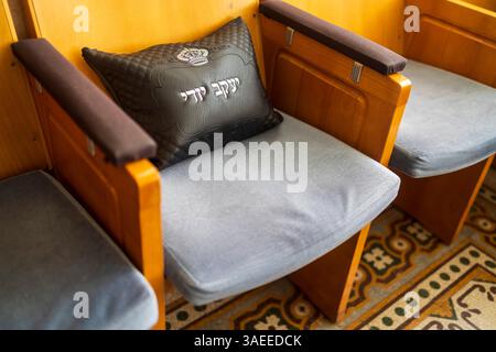 Haifa, Israel, 5. April 2025, Innenansicht einer Aram-Zzova-Synagoge. Nahaufnahme von Holzsitzen mit grauen Kissen und einem schwarzen Kissen mit Hebre Stockfoto