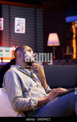 Junge Erwachsene prüfen den Finanzsaldo und arbeiten an Bilanzierungsanalysen, um das Umsatzwachstum des Unternehmens zu Hause sicherzustellen. afroamerikaner hat einen Remote-Job mit Wirtschaftsstatistiken. Stockfoto
